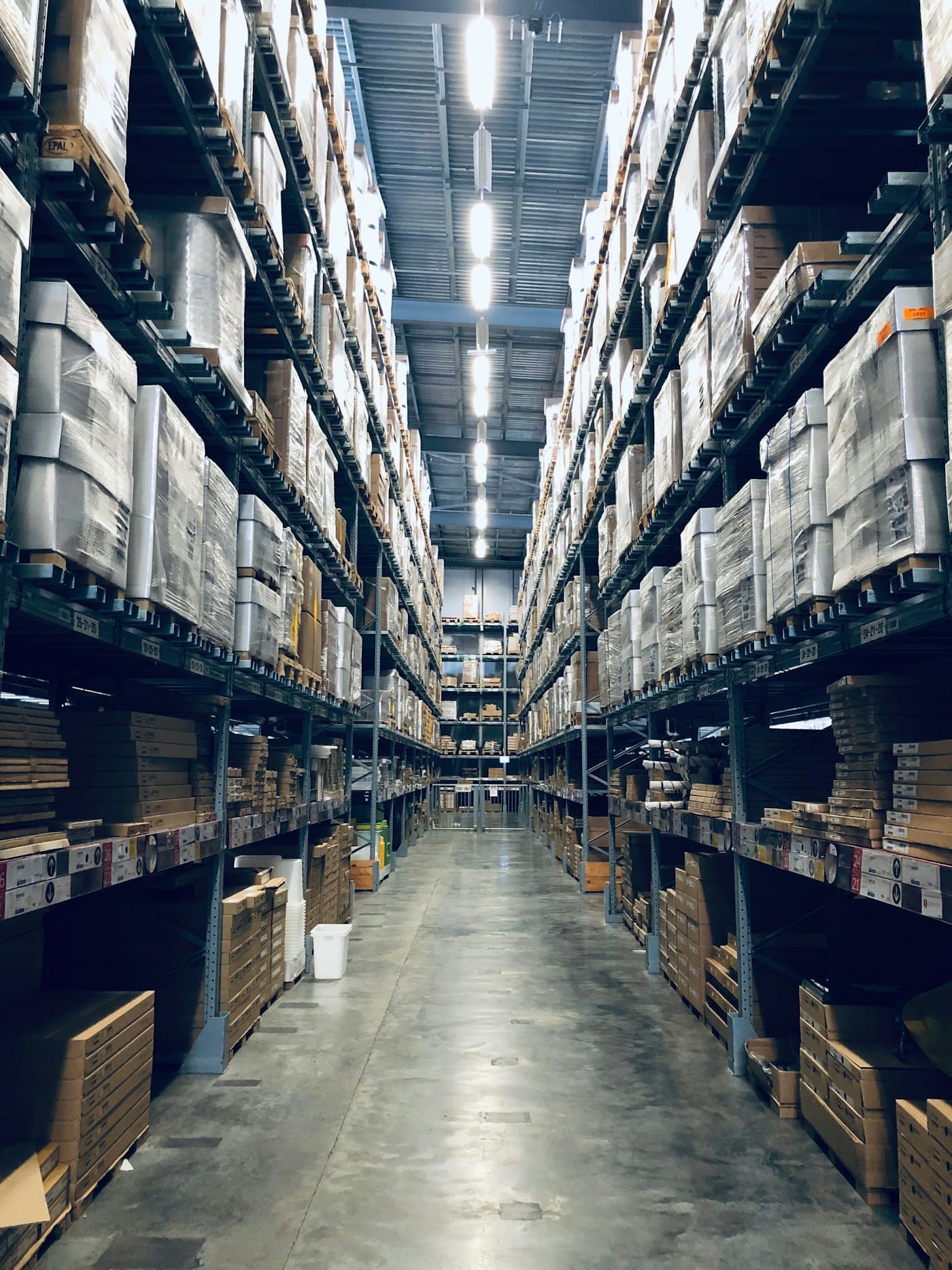 Pasillo de almacén con tarimas en racks altos